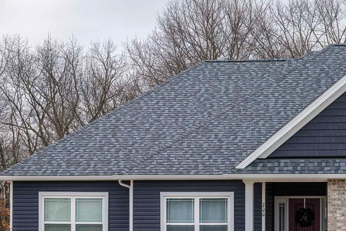 Newly installed gray architectural shingles on a St. Louis home with navy blue vinyl siding and white trim.