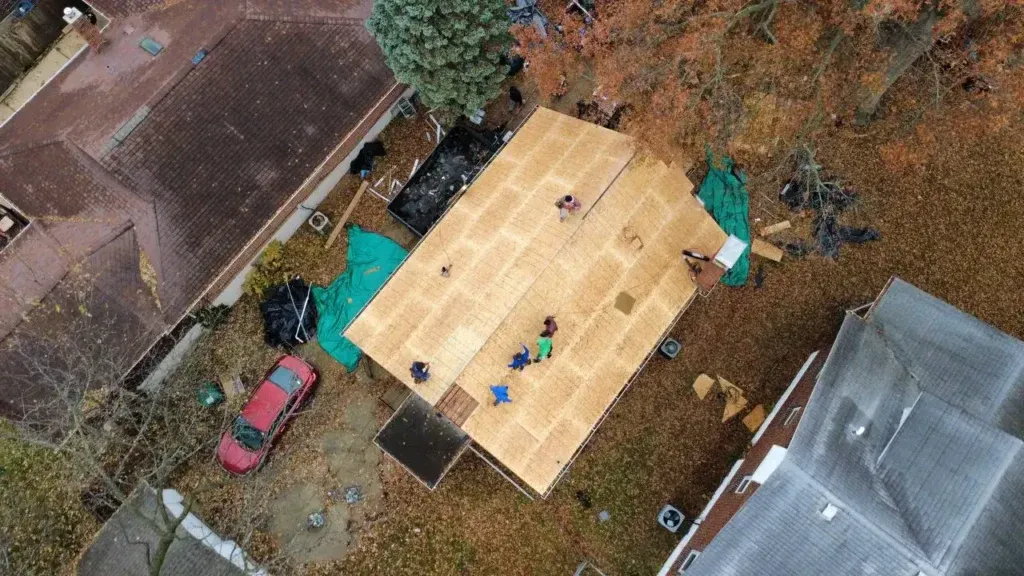 Roofing crew working on fresh OSB roof decking during a full roof replacement