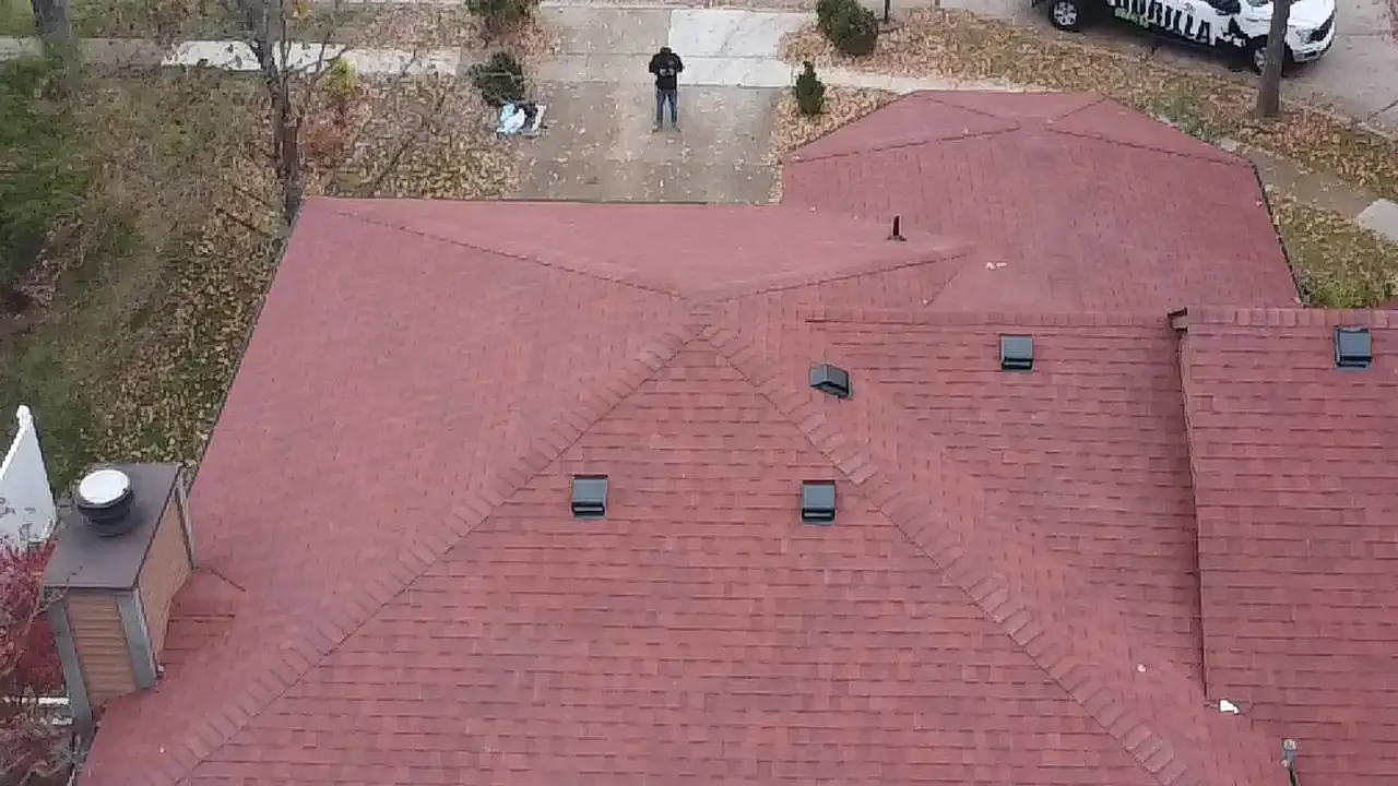 Aerial drone view of a large red asphalt shingle roof with multiple vents on a St. Louis home.
