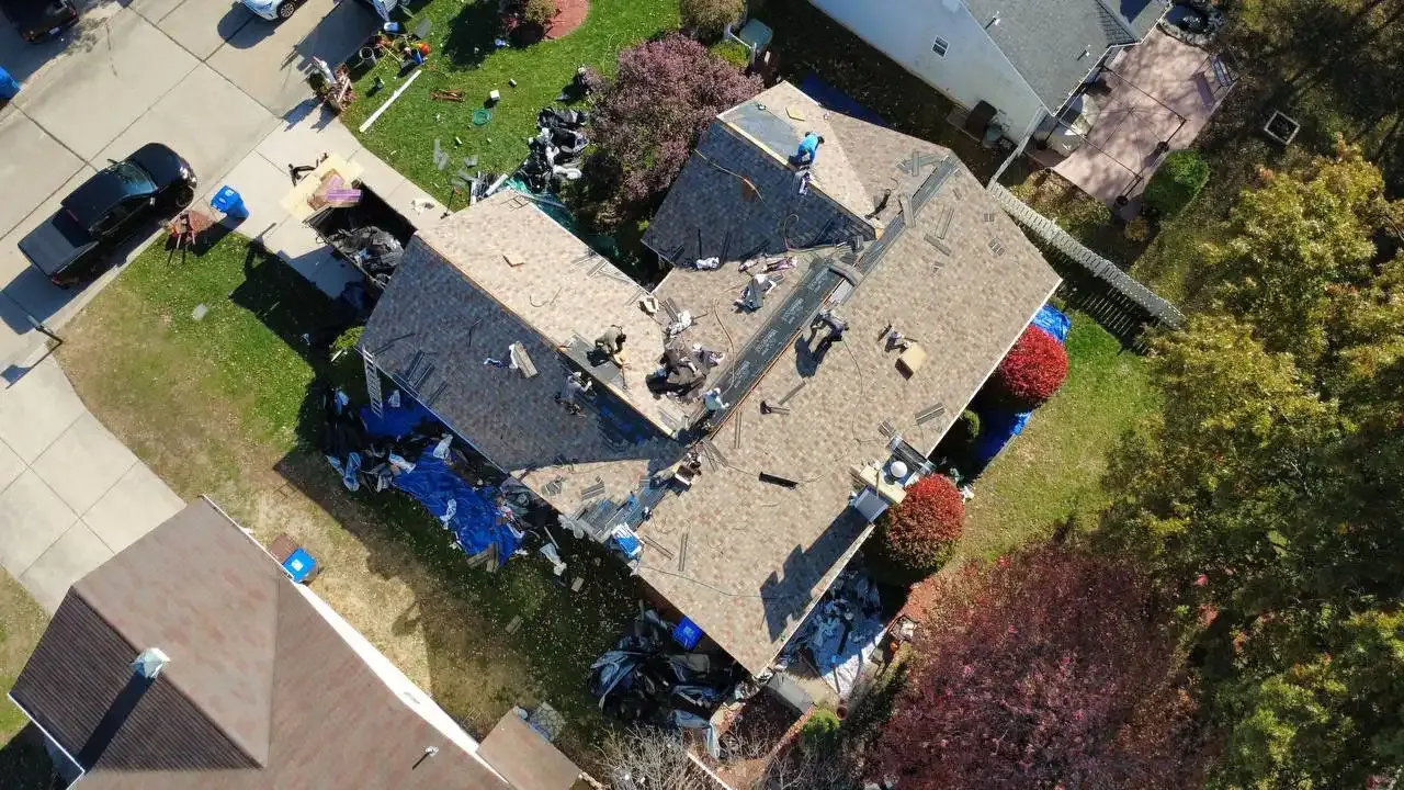 Aerial drone view of a residential roof replacement in progress with workers and debris visible in St. Louis, MO