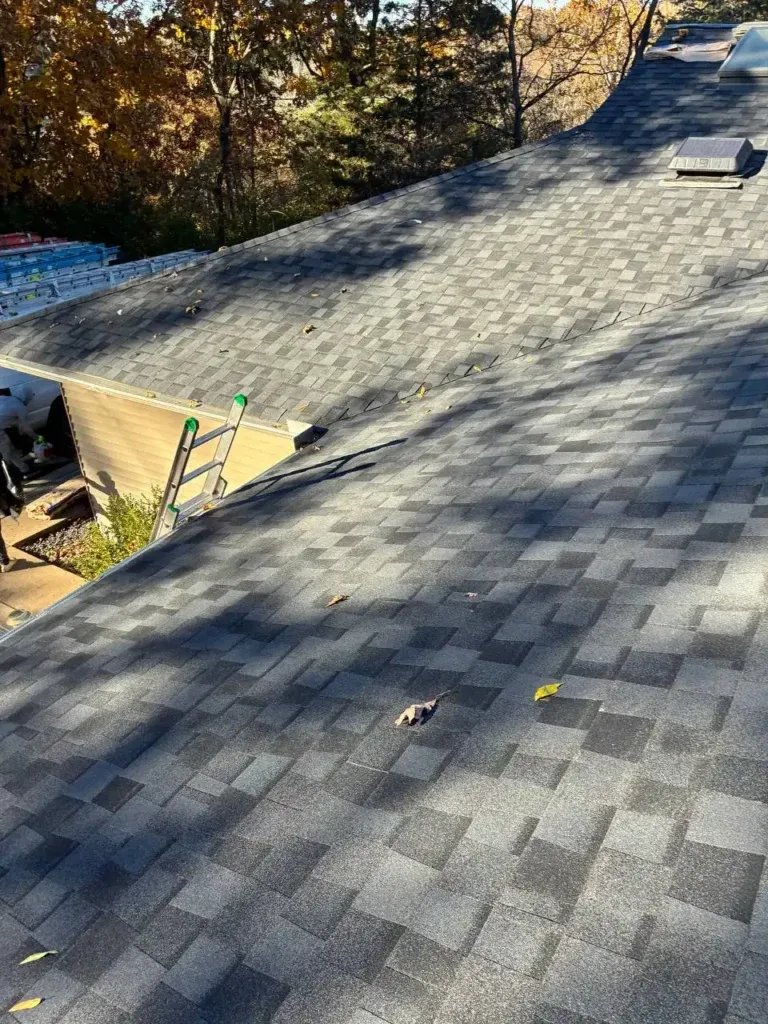 A freshly completed gray asphalt shingle roof with clean coursing, a roof vent, and a skylight