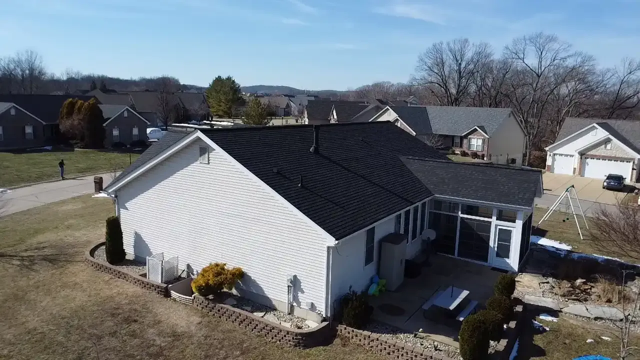 Aerial drone view of a residential home with a new dark asphalt shingle roof in St. Louis, MO neighborhood.