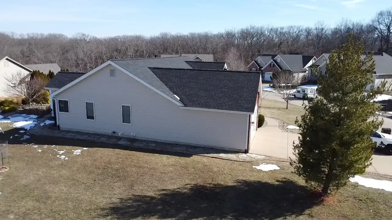 Aerial drone view of a suburban home with dark asphalt shingle roof in winter, St. Louis MO neighborhood
