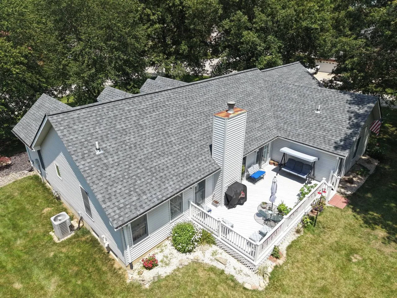 Aerial view of a residential home with gray asphalt shingle roof, white deck, and chimney in St. Louis, MO
