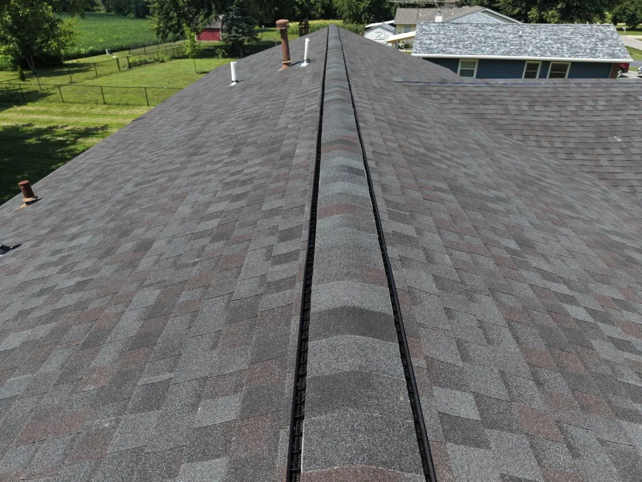 Aerial view of newly installed gray asphalt shingle roof with ridge vent running along the peak of a St. Louis home.