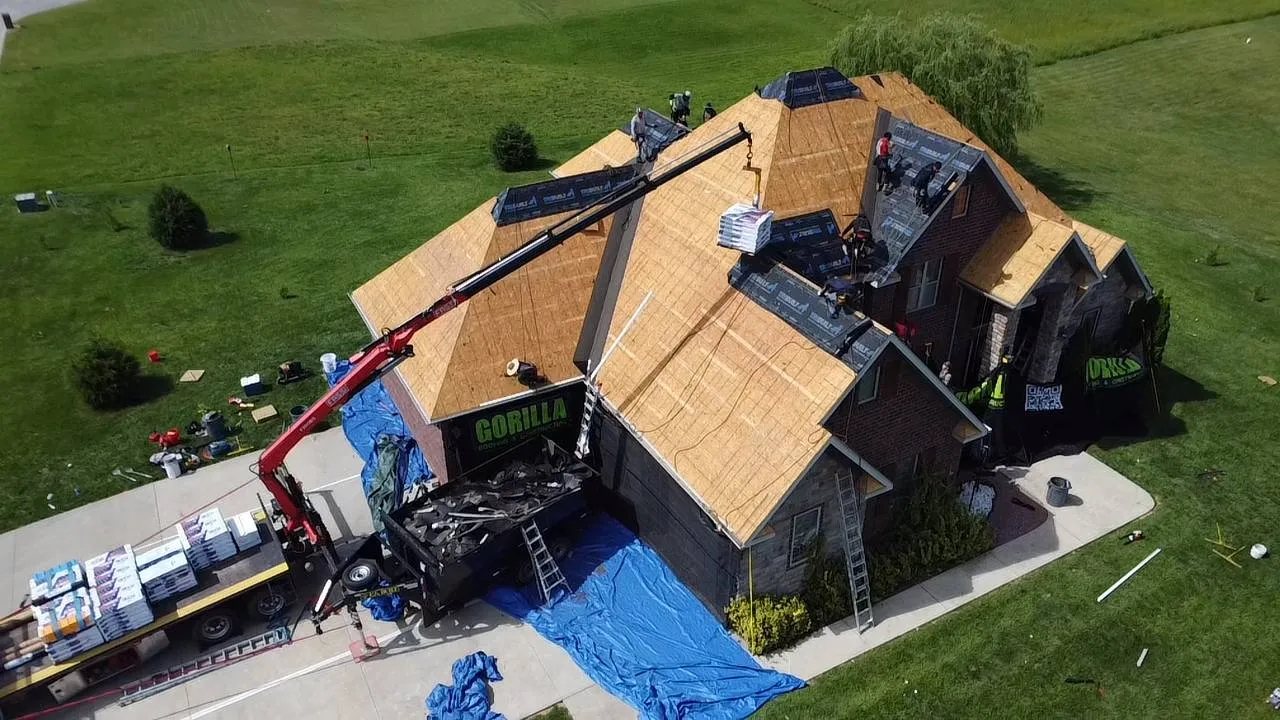 Aerial view of Gorilla Roofing crew replacing shingles on a large brick home in St. Louis during an insurance restoration project.