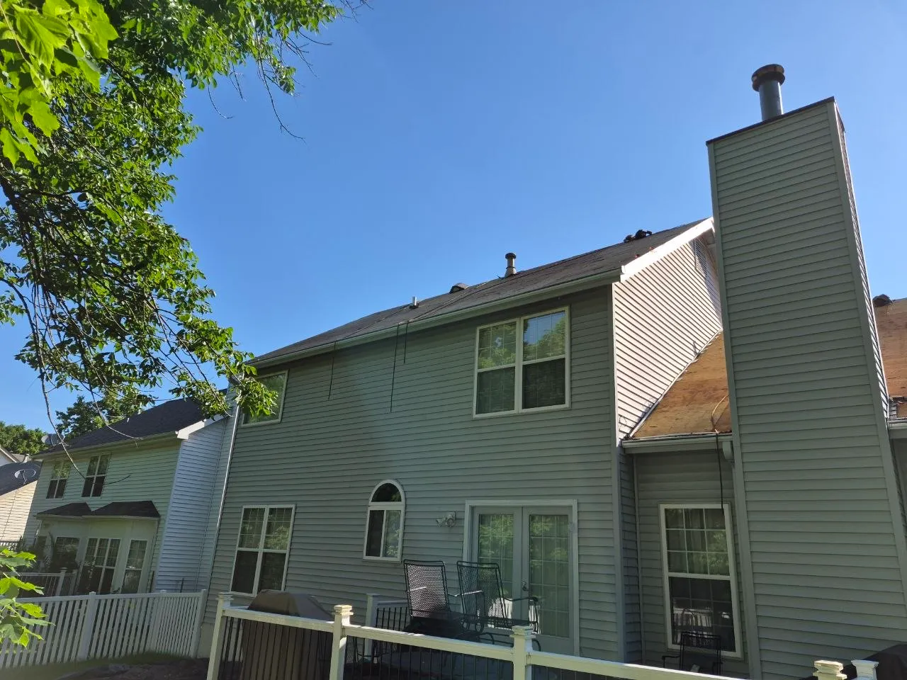 Rear view of a two-story home in St. Louis with aging shingle roof and exposed wood decking during replacement.