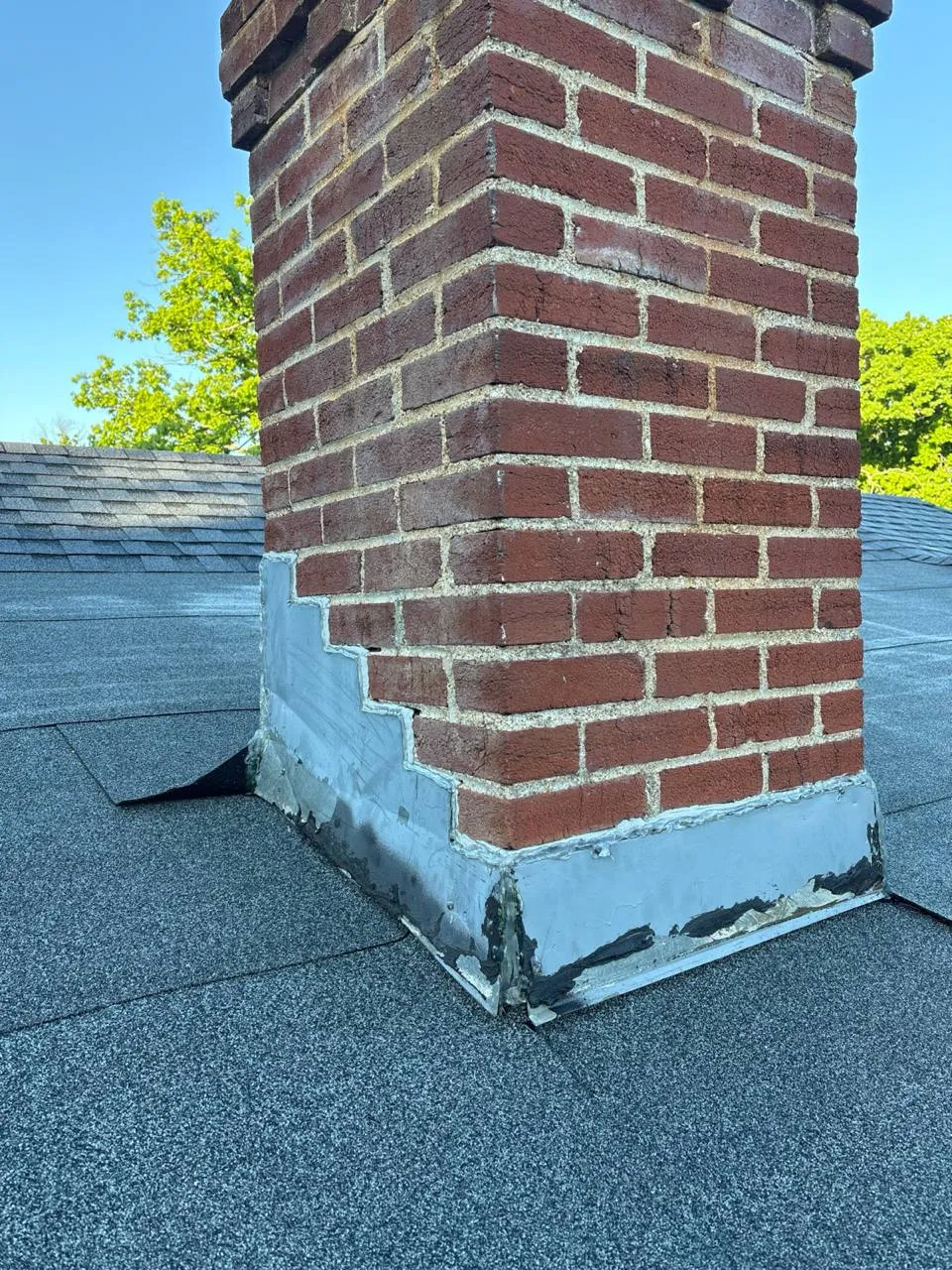 Cracked, peeling sealant on the flashing of a brick chimney on a St. Louis roof