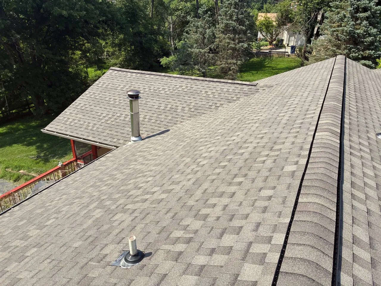 Newly installed gray architectural shingle roof with metal pipe vents on a St. Louis home surrounded by trees