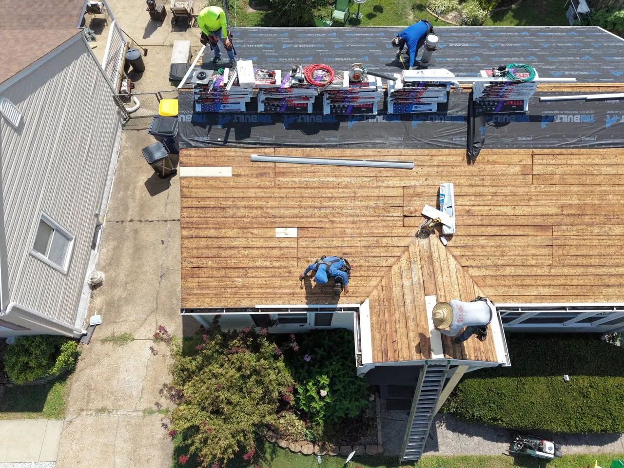 Aerial drone view of roofing crew installing new shingles and underlayment on a residential home in St. Louis