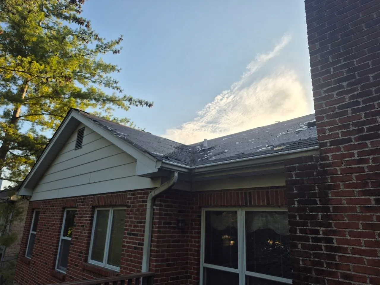 Hail-damaged asphalt shingle roof on a brick St. Louis home showing scattered impact marks and granule loss.
