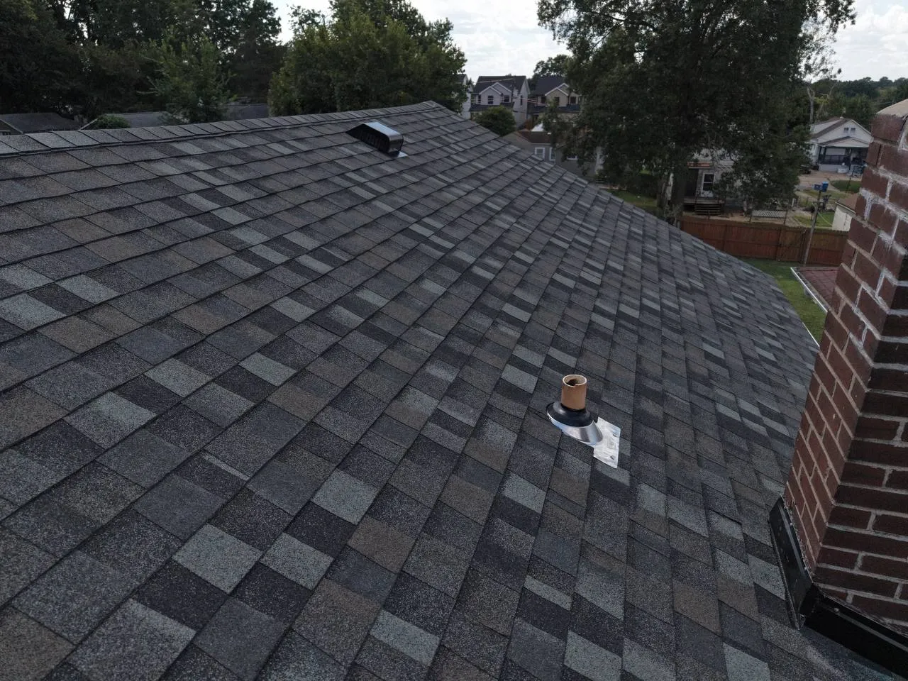 Aerial view of newly installed gray architectural shingles on a residential roof in St. Louis, MO with brick chimney.