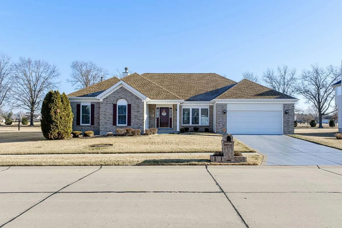 Brick ranch-style home in St. Louis with architectural shingle roof, two-car garage, and clean concrete driveway.
