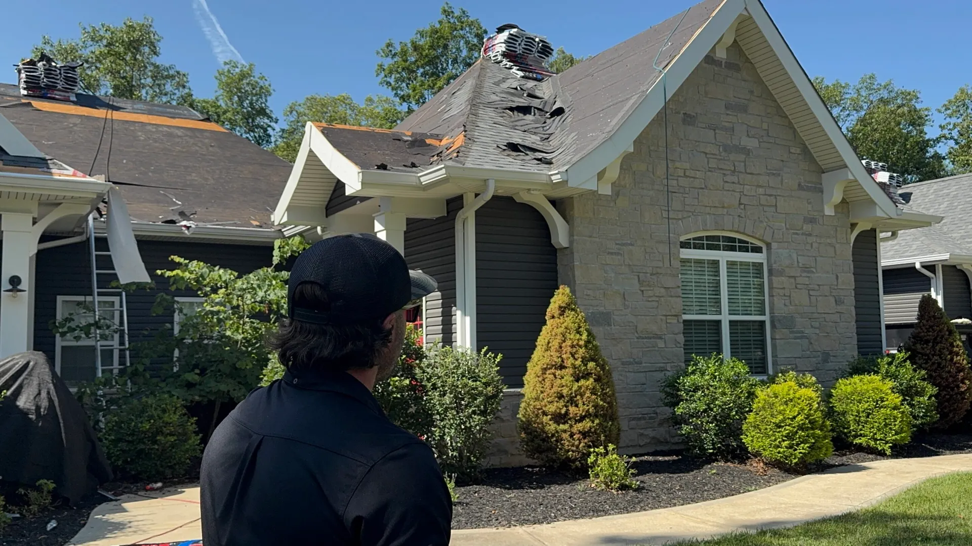 Homeowner inspecting severe storm damage to a residential roof in the St. Louis metro area