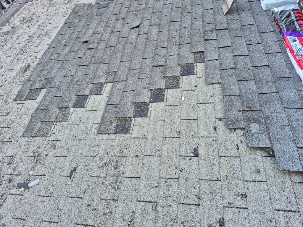 Damaged asphalt shingle roof in St. Louis showing missing shingles, granule loss, and worn areas needing replacement.
