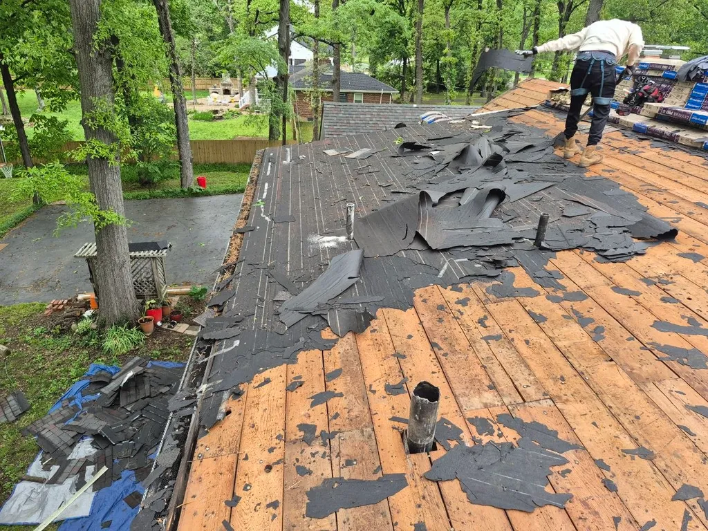 Roofer removing old shingles during full roof tear-off on a residential home in St. Louis, MO