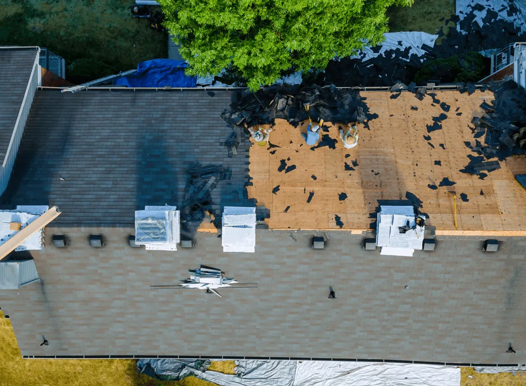 Aerial drone view of roof replacement in progress showing torn-off shingles and exposed decking on St. Louis home